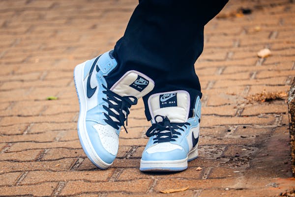 Close-up of fashionable blue and white Nike sneakers on a brick path, showcasing modern street fashion.