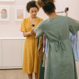 Two women engaged in selecting and noting down outfits in a boutique setting.